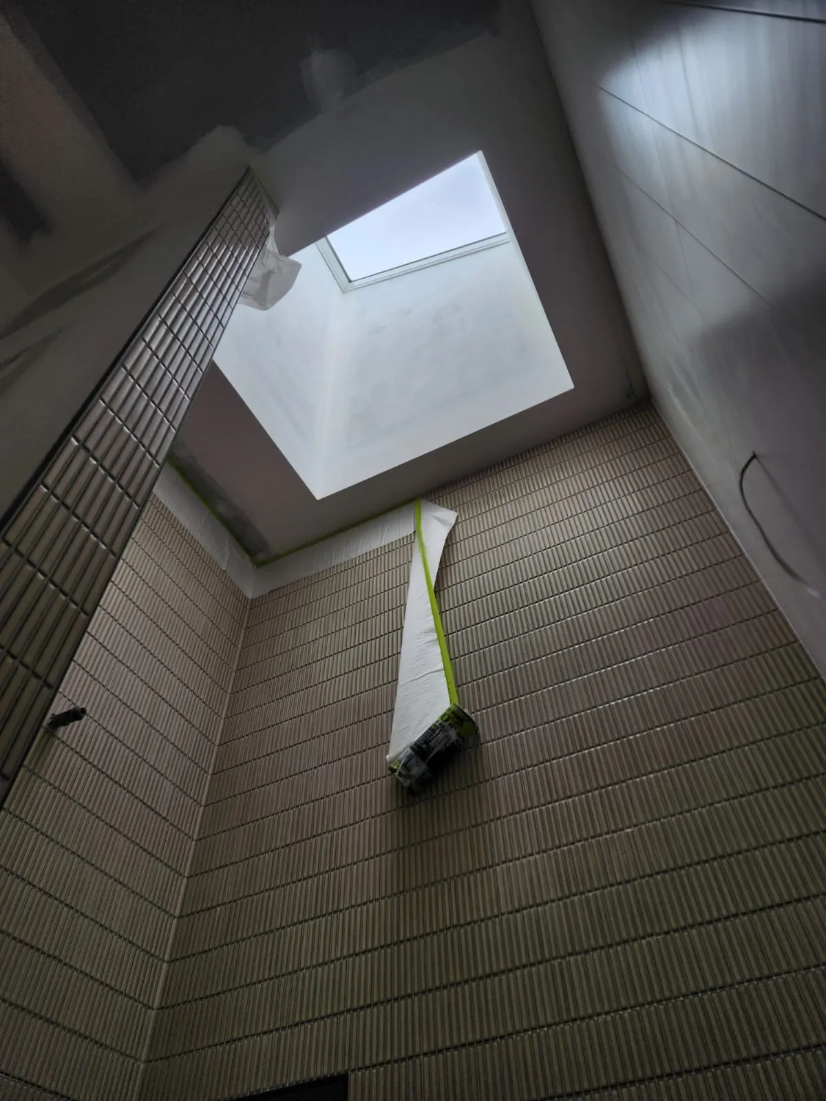 Tiled stairwell void with a skylight, masked and prepared for painting