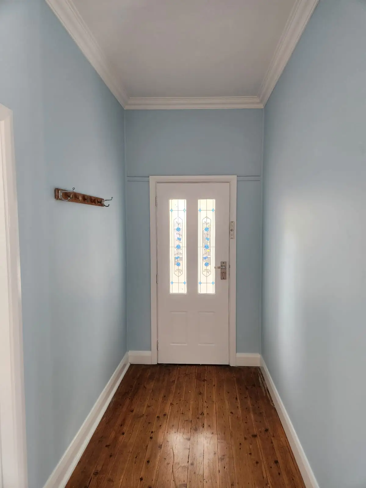Blue hallway with white trim and a stained-glass entry door