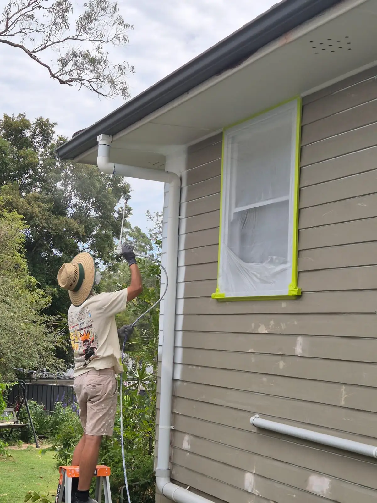 Painter spraying an exterior wall on a Newcastle home